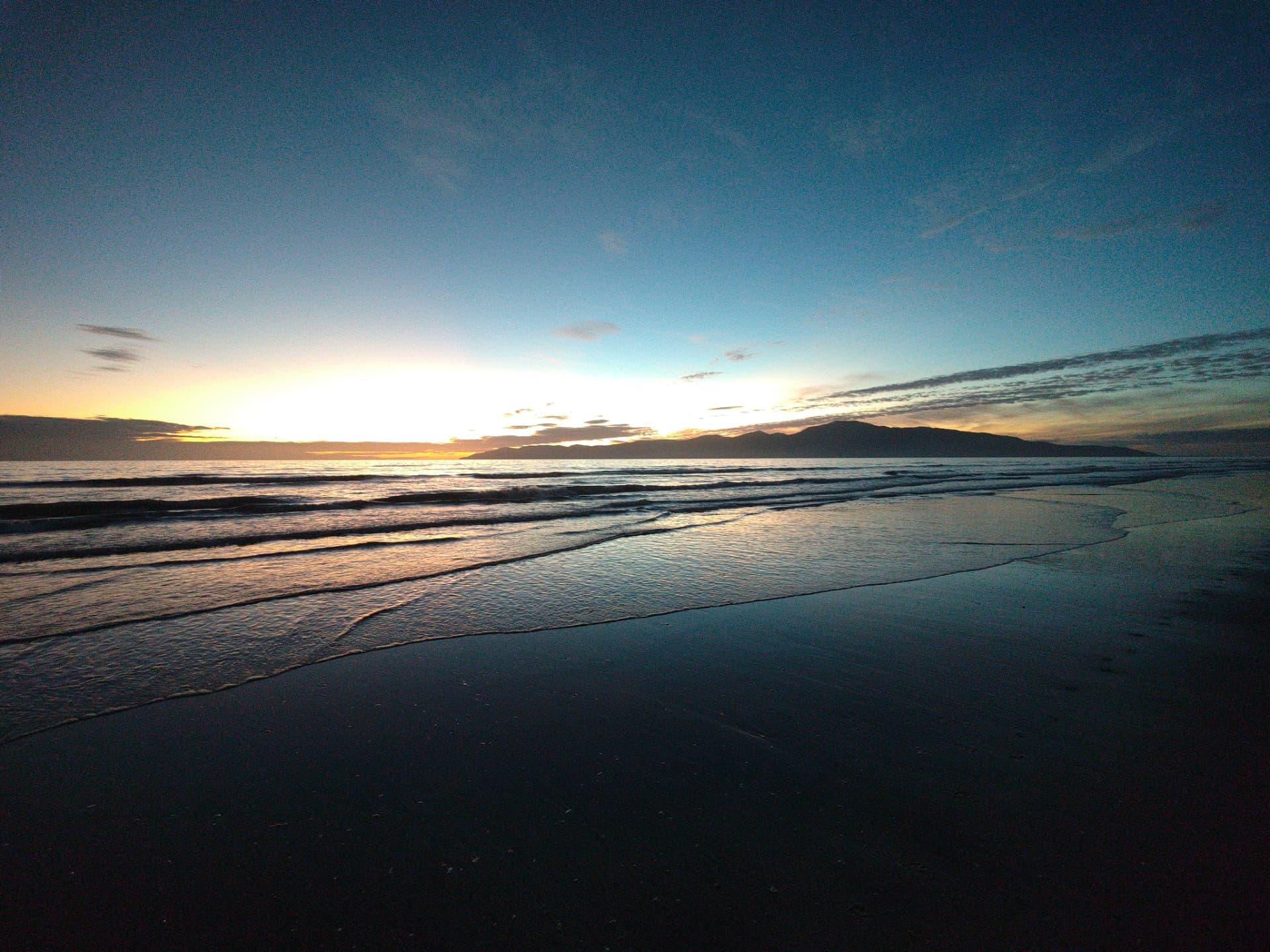 Sunset over the tide line at a wide Canterbury beach